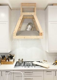 a stove top oven sitting inside of a kitchen next to white cupboards and drawers