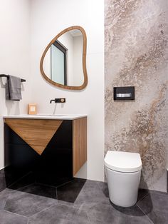 a white toilet sitting next to a bathroom sink under a large mirror on the wall