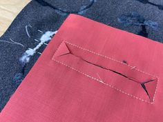 a red piece of fabric with stitching on it sitting next to a pair of scissors