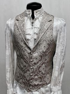 Note: These vests are very fitted. Check the size measurements below very carefully to find the size that will fit you best. A Victorian gentleman's vest with class. Great for formal occasions, can be worn under a suit jacket or by itself. Made in rich silver brocade fabric with an intricate design woven in with silver thread. With black satin lining inside and on the back. This vest has a very flattering tapered fit and ties in back with satin belting so it can be made tighter in the waist. Fas Elegant Blazer With Vest For Semi-formal Occasions, Elegant Semi-formal Blazer With Vest, Elegant Tailored Three-piece Suit With Vest, Formal Fitted Three-piece Suit With Vest, Formal Fitted Sleeveless Vest, Classic Tailored Wedding Vest, Fitted Sleeveless Vest For Wedding, Elegant Fitted Three-piece Suit With Vest, Elegant Fitted Suit With Vest