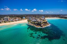 an aerial view of the beach and ocean with buildings in the distance, taken from above