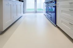 an empty kitchen with white cabinets and blue oven