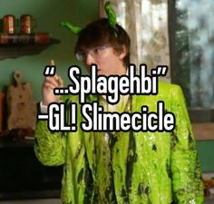 a man in green shirt standing next to a wall with words on it that say, splagebi - ol slimeciel