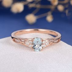 an oval blue topazte and diamond ring on a white cloth with flowers in the background