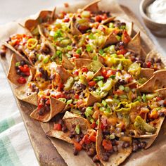 a wooden cutting board topped with lots of nachos