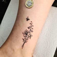 a small tattoo on the ankle of a woman's foot with flowers and a bee