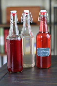 three glass bottles with labels on them sitting on a table