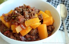 a bowl filled with meat and vegetables on top of a table next to a fork