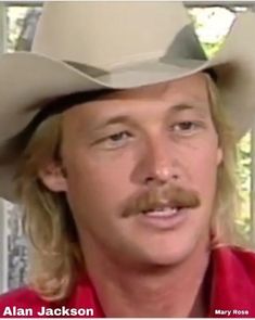 a close up of a person wearing a cowboy hat with a moustache on his face