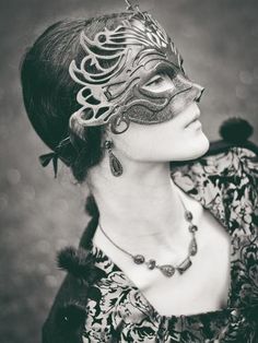 a woman wearing a masquerade and jewelry in black and white with an ornate mask on her face