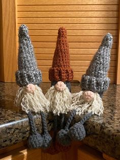 three crocheted gnomes sitting on top of a counter