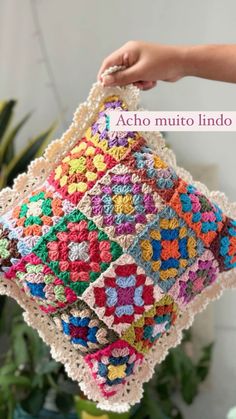 a crocheted pillow is being held by a woman's hand with the words aco muto lindo on it