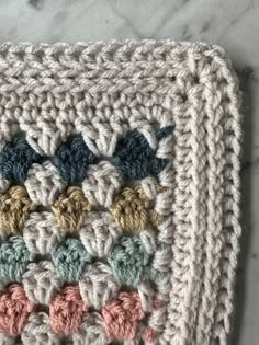 a crocheted dishcloth with multicolored leaves on it sitting on a marble surface