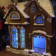 a large gingerbread house with windows and snow on the roof is decorated for christmas