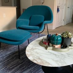 a blue chair and ottoman in a living room next to a coffee table with succulents on it