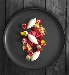 a black plate topped with food on top of a wooden table