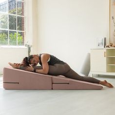 a woman laying on top of a bed in a living room next to a window