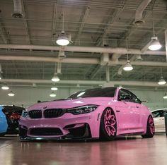 a pink car parked in a garage with other cars