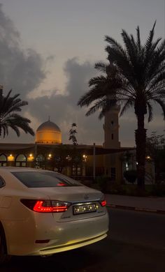 a white car parked in front of a tall building with a dome on it's roof