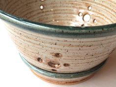 a close up of a ceramic bowl on a white surface with drops of water in it