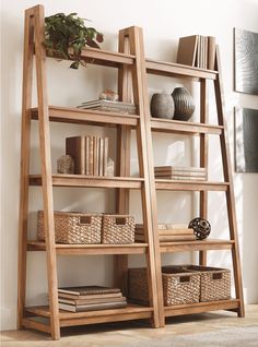 a wooden ladder shelf with baskets and books on it in front of a white wall