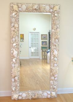 a mirror that is sitting on the floor in front of a wall with shells and seashells