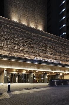 the royal hotel seoul is lit up at night with lights shining on it's facade