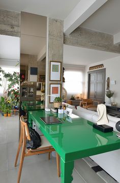 a green table in the middle of a living room with chairs and plants on it