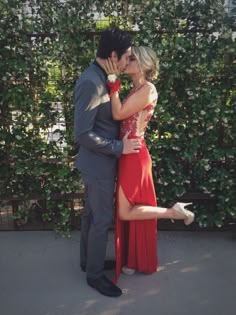 a man and woman are kissing in front of some bushes