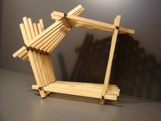 a wooden structure made out of sticks on a table top with a shadow behind it