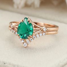 a ring with an oval cut green stone surrounded by small white diamonds on a cushioned surface