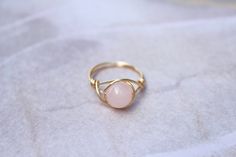 A pretty rose quartz gemstone ring wrapped in gold or silver jewellery wire. Rose Quartz is a milky light pink stone. {Details} 💍 * 8mm rose quartz bead (please note that gemstone beads are usually treated to enhance colour and appearance of the stone) * Non tarnish yellow gold (pictured), rich gold, copper or silver plated wire - also available in sterling silver * Available is sizes 3-13 including half sizes, chose size before adding to cart {Jewelry care} 💍 To ensure lasting quality of your Delicate Wire Wrapped Ring Jewelry, Delicate Wire Wrapped Promise Ring, Elegant Handmade Rose Quartz Rings, Dainty Wire Wrapped Crystal Ring, Elegant Wire Wrapped Crystal Ring For Wedding, Delicate Wire Wrapped Jewelry, Gold Wire Ring, Wire Rose, Jewellery Wire