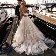 a man and woman standing on a dock next to boats