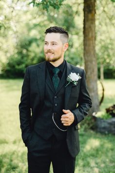 a man in a suit standing next to a tree