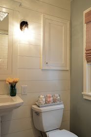 a white toilet sitting next to a sink in a bathroom under a window with blinds