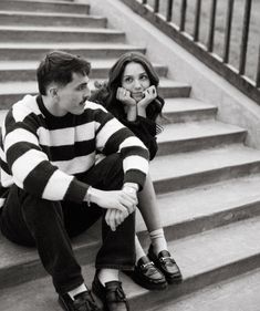 a man and woman sitting on the steps talking on their cell phones