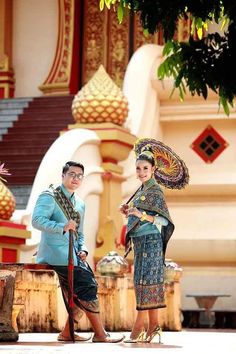 two people dressed in traditional thai garb and holding parasols