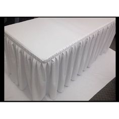 the table is covered with white cloths and has pleated edges on each side