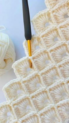 the crochet pattern is being worked on with a knitting needle and yarn ball