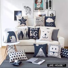 a living room filled with lots of pillows on top of a white couch next to pictures