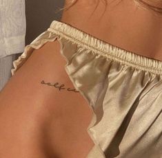 the back of a woman's shoulder with a small tattoo on her left arm