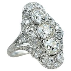 an old - fashioned diamond ring with three stones in the center and two rows of diamonds on