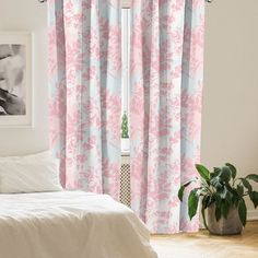 a bedroom with pink and blue curtains, white bedding, and a plant in the corner