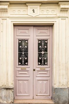 two pink doors with wrought iron bars on the front of an old building in europe