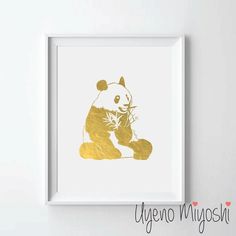 a gold foiled panda bear sitting on the ground in front of a white wall