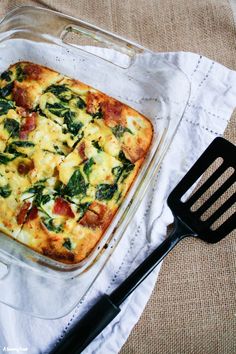 a casserole dish with spinach and cheese in it next to a spatula