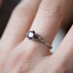 a close up of a person's hand with a ring on their finger and an amethyst