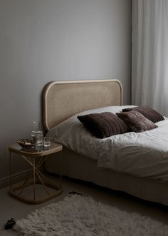 a bedroom with a bed, side table and window