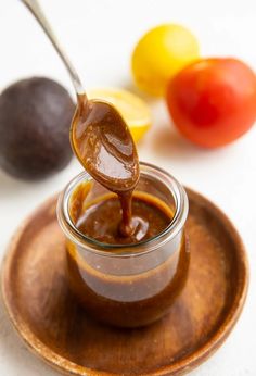 a spoon full of chocolate sauce on top of a plate next to tomatoes and lemons