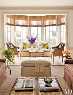 a living room filled with lots of furniture next to two large windows covered in blinds